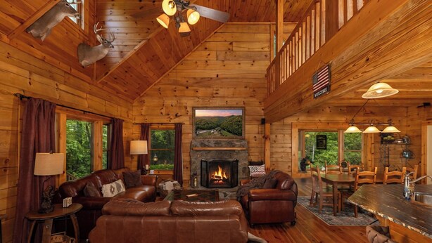 L’intérieur d’un chalet en bois comprend une cheminée, des meubles en cuir et un coin repas.