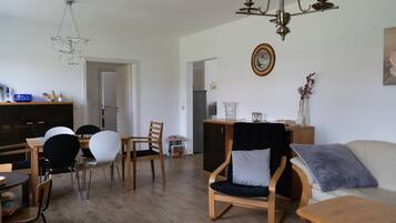 A modern living room with a dining area, wooden furniture, a chandelier, and a painting on the wall.