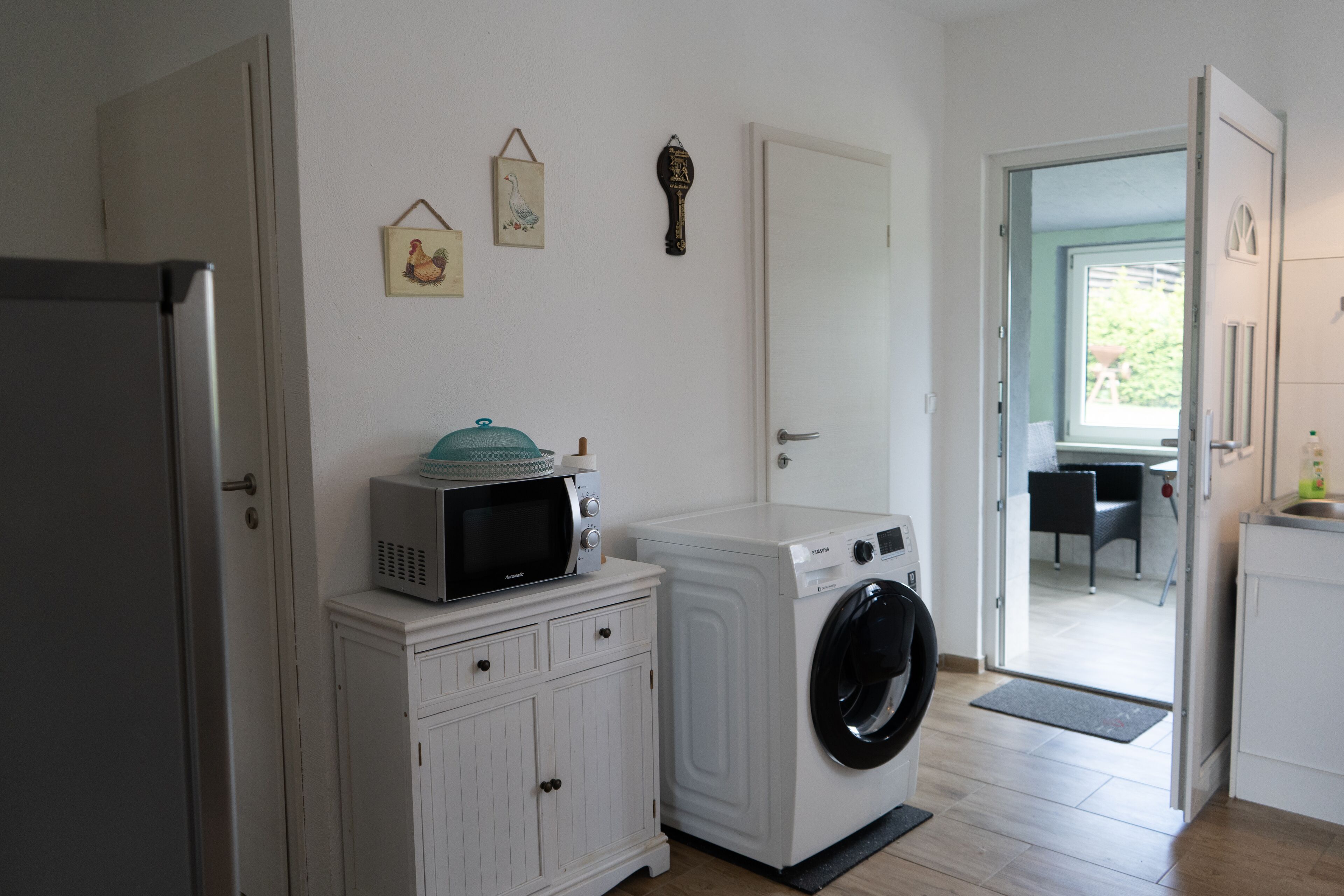 Une petite buanderie comprenant un lave-linge, un sèche-linge et un four à micro-ondes placés sur un meuble.