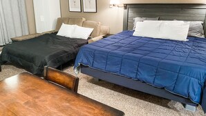 A hotel room with two beds, a wooden table, a sofa, and a wall-mounted lamp. - Ski In/Ski Out Studio - Perfect Get Away (Brian Head)