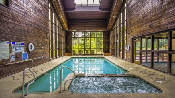 An indoor swimming pool with wooden walls, a hot tub, and a view of trees through large windows. - Ski In/Ski Out Studio - Perfect Get Away (Brian Head)