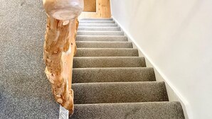 A staircase with a wooden handrail and carpeted steps.