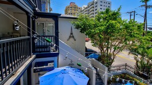 A balcony with a blue umbrella, a staircase, and a building with an 'A' sign.
