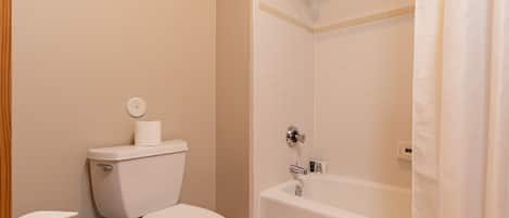 Een badkamer met toilet, douche en bad.