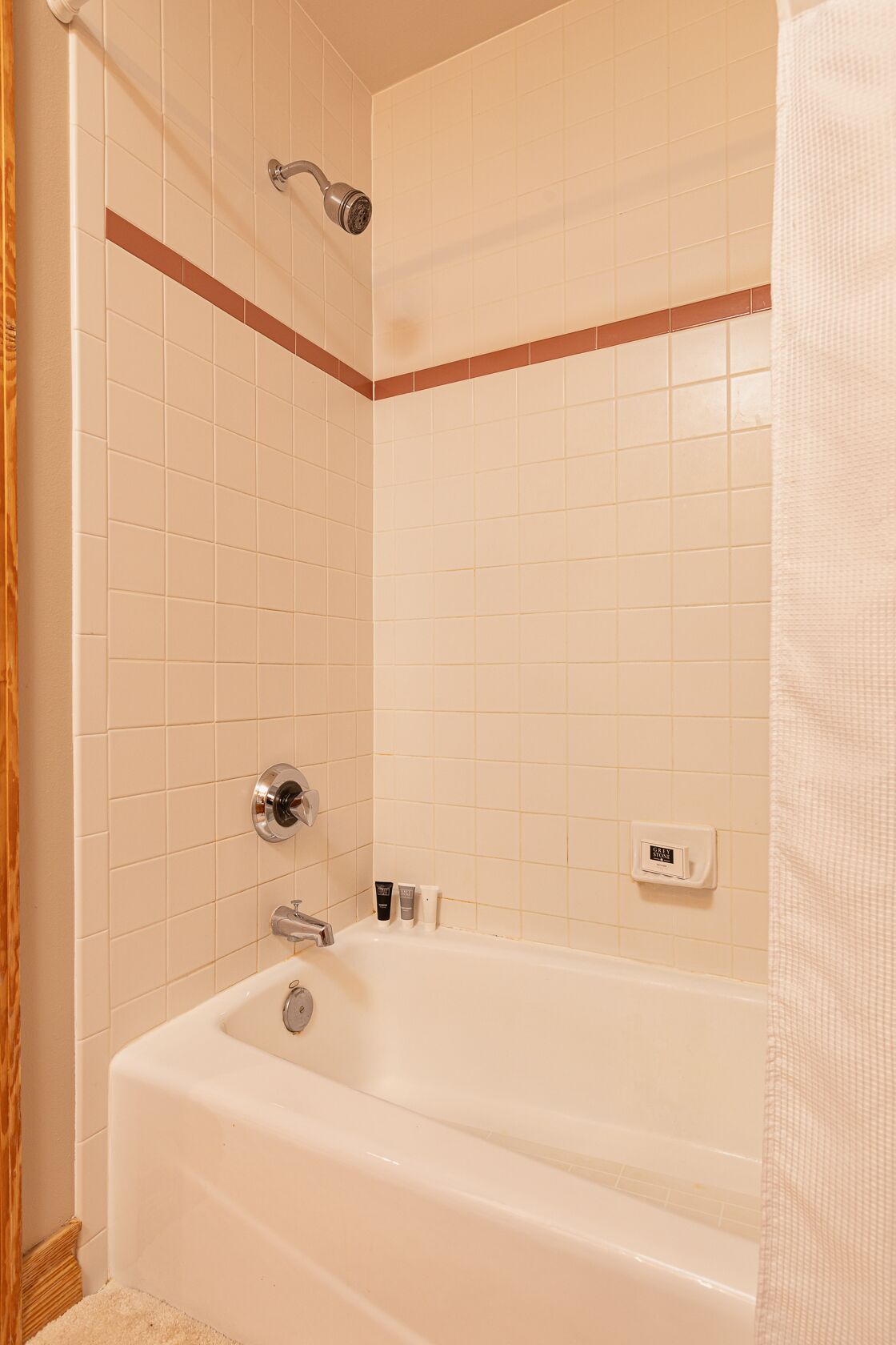 A bathroom with a bathtub, a showerhead, and a towel rack.