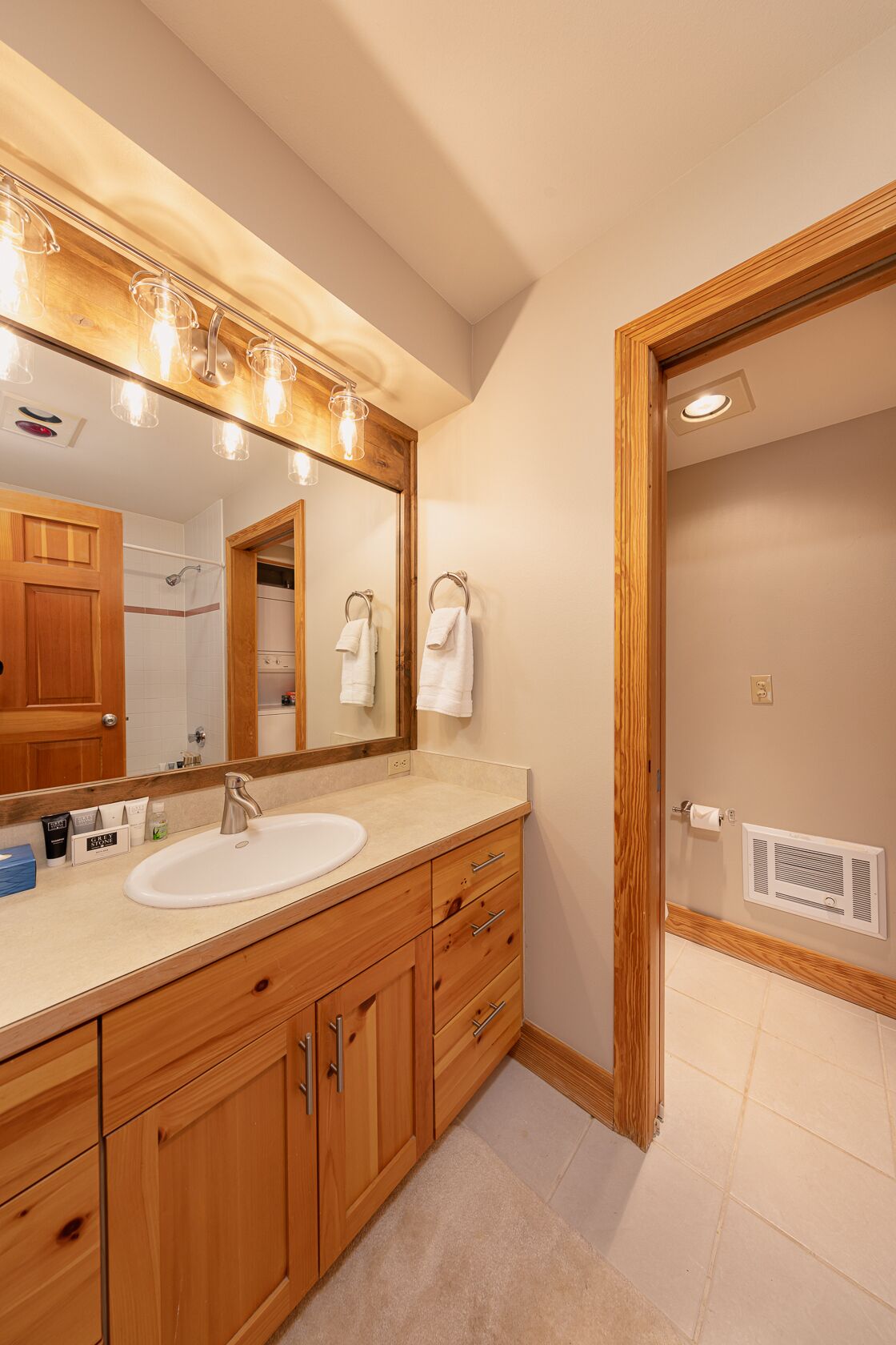 A bathroom with a wooden vanity, a large mirror, and a shower.