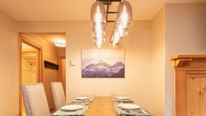 Un comedor con una mesa de madera, sillas y una araña.