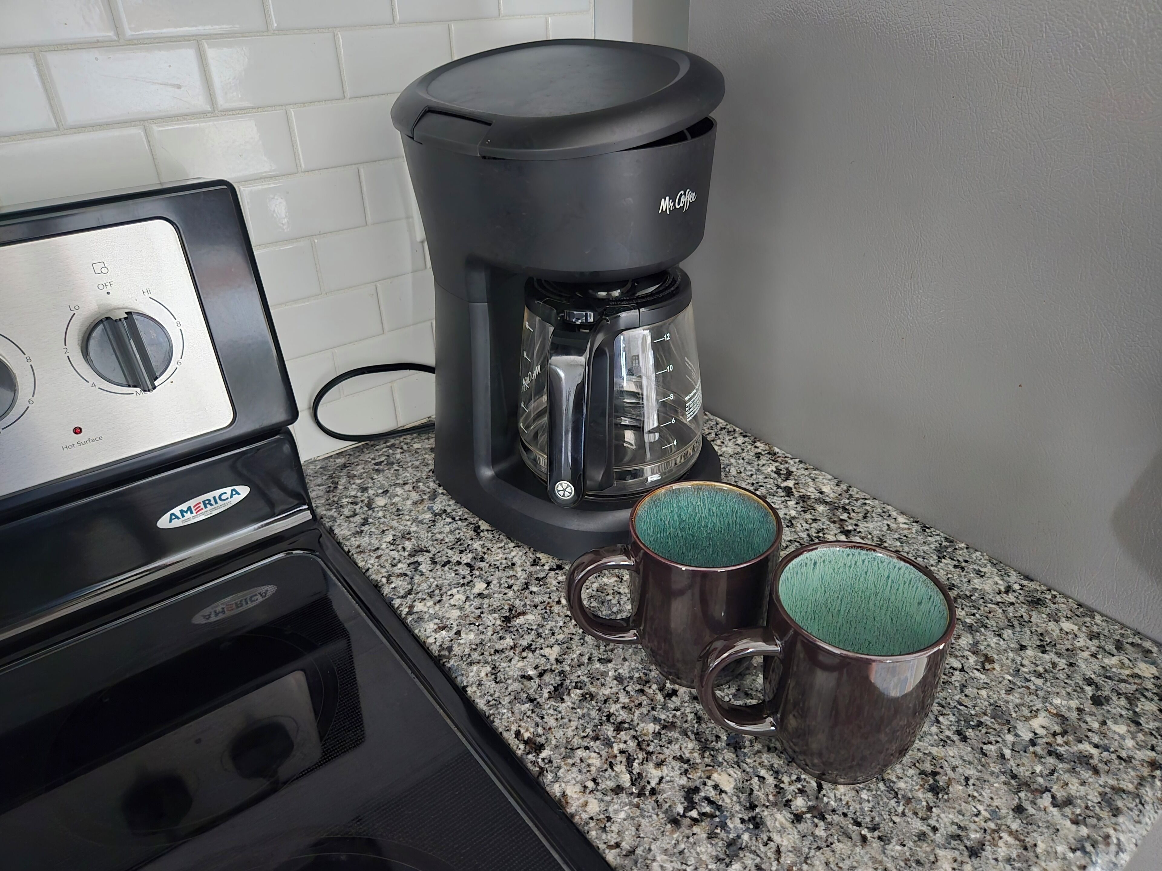 Eine Küche mit Kaffeemaschine, zwei Tassen und einem Herd.