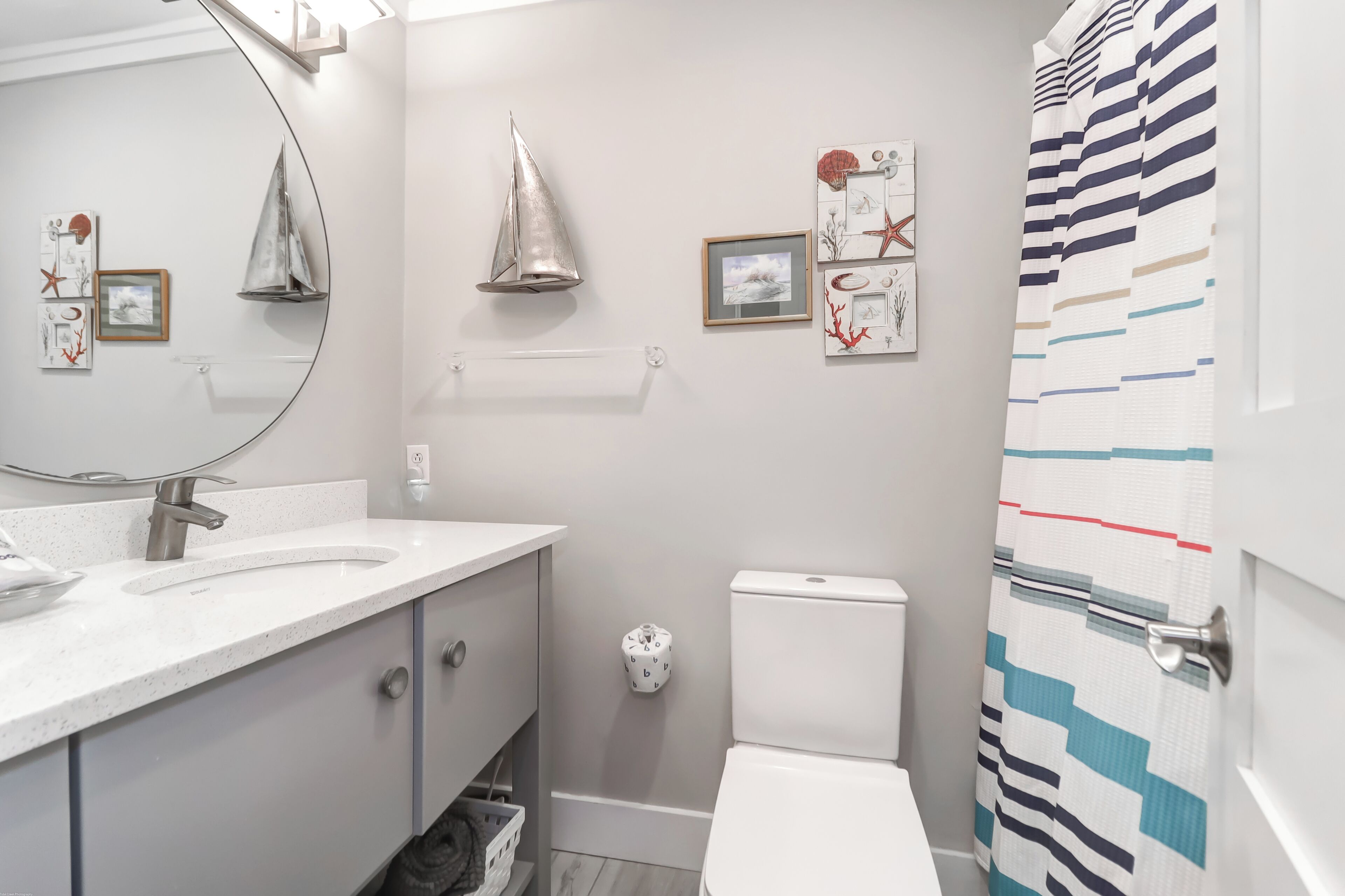 A modern bathroom with a white sink, a toilet, and a shower curtain.