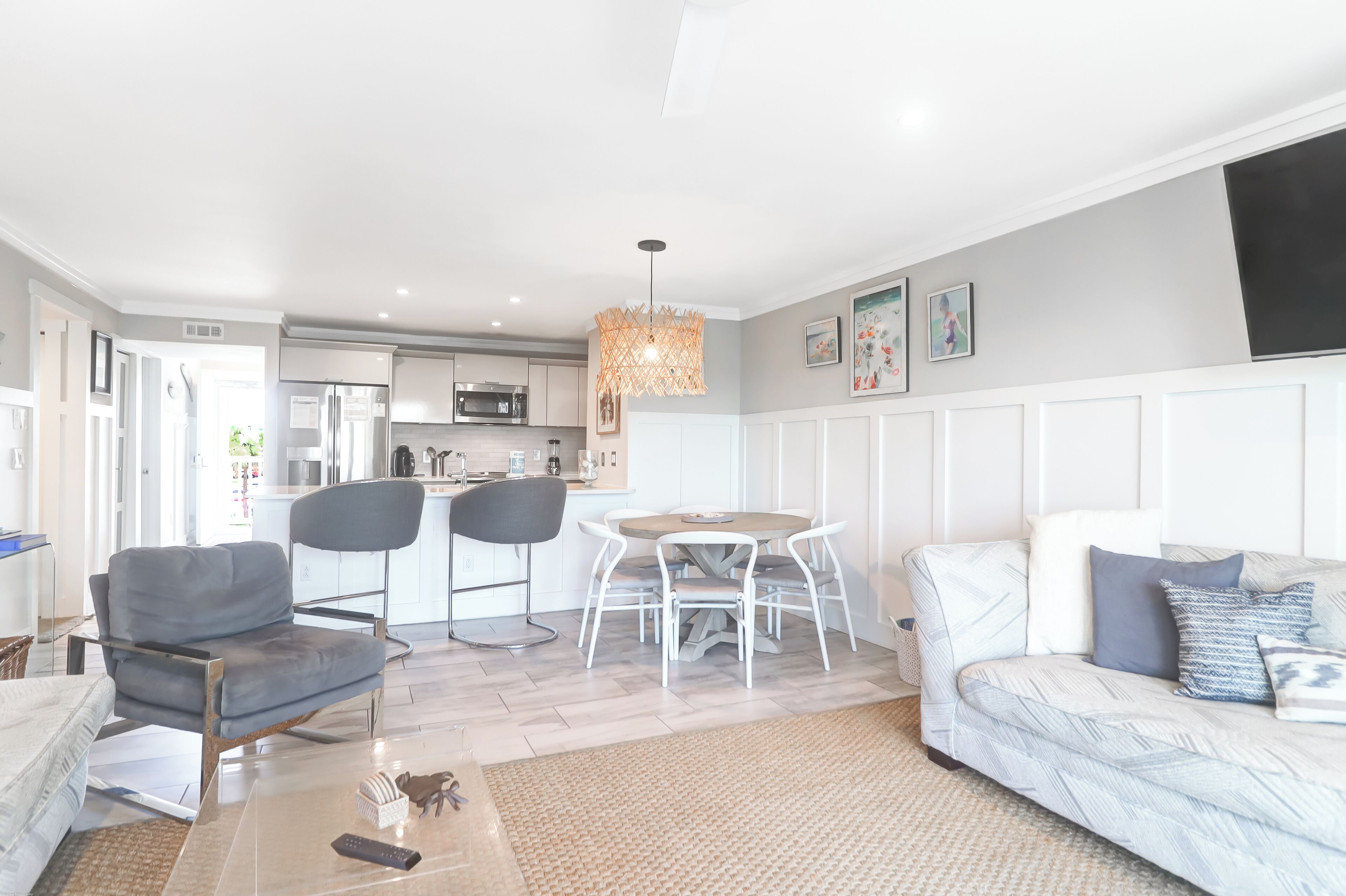 Una sala de estar moderna con un sofá, sillones, una mesa de comedor y una cocina al fondo.