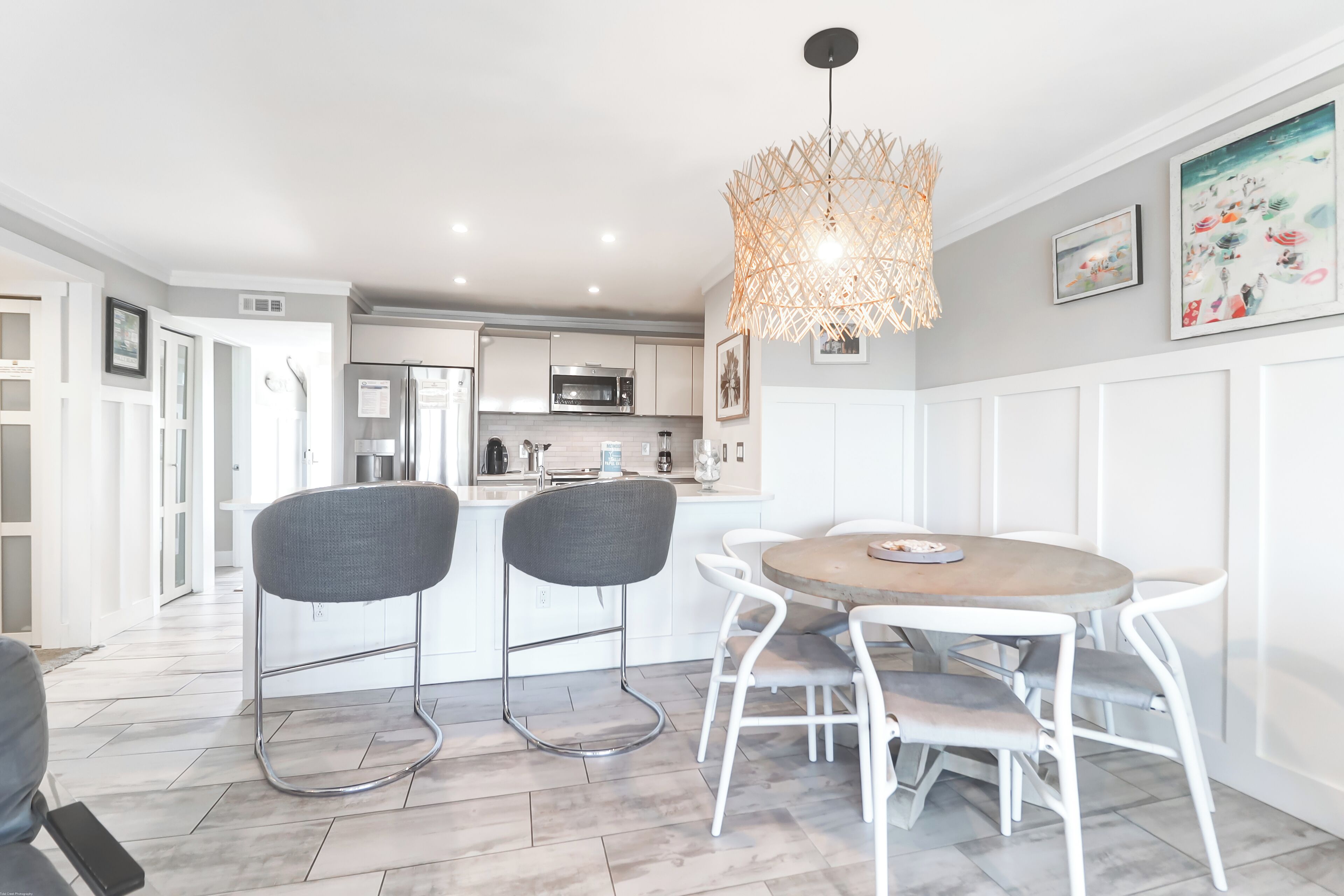 A modern kitchen with white cabinetry, a central island, and a dining area with a round table and chairs.