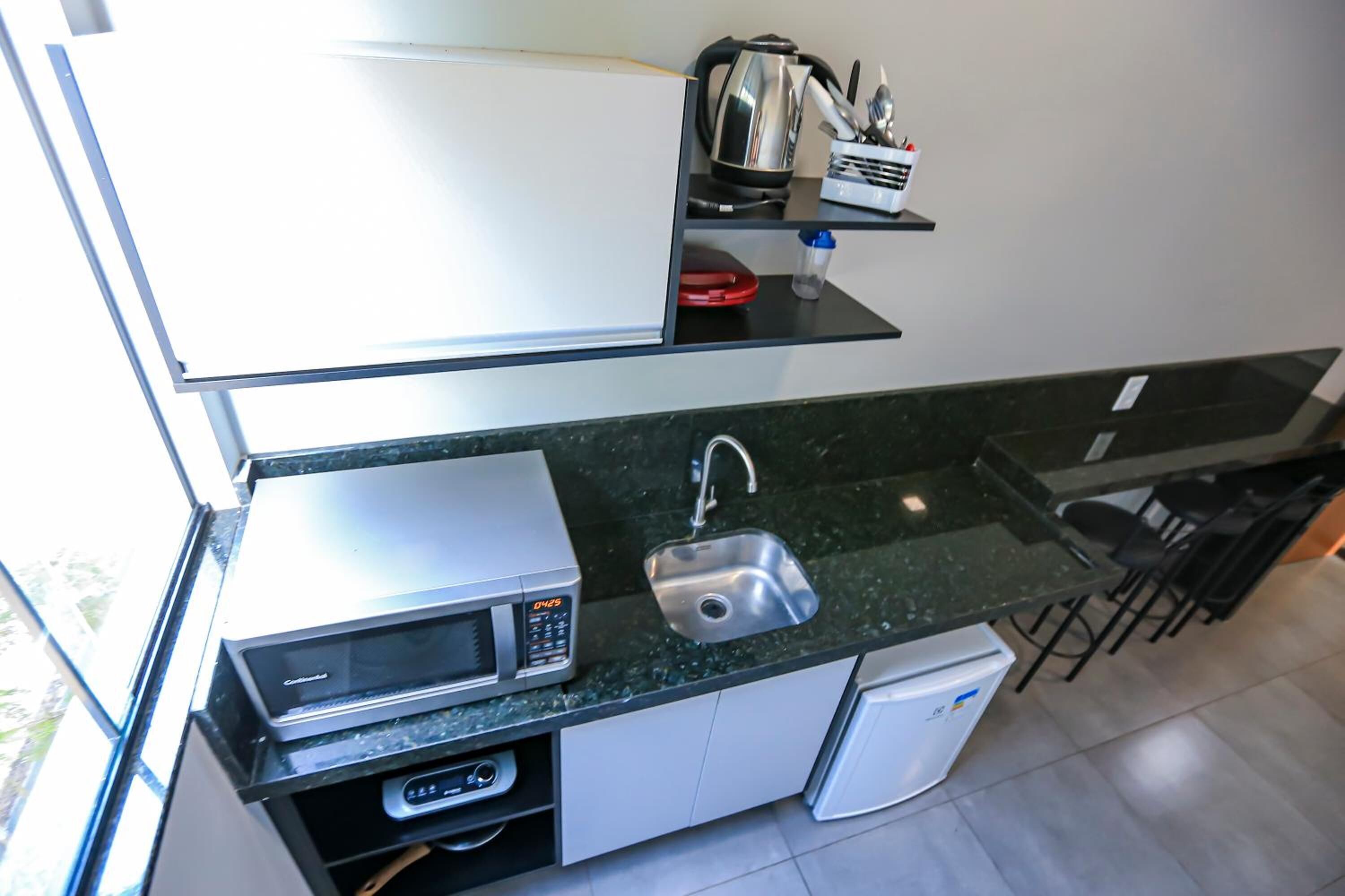 A compact kitchen with a microwave, sink, and a small refrigerator.