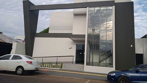 A modern building with a large glass entrance and a staircase leading to the upper floor.