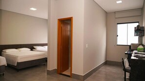 A modern hotel room with a bed, a desk, and a chair.
