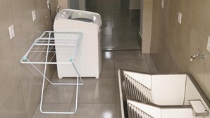 A corridor with a laundry area, a vent, and a mounted television.