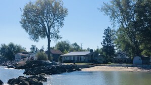 Una propiedad frente al lago con una casa, un muelle y una playa de arena.
