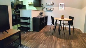 A compact living space with a kitchenette, a dining area with a table and chairs, and a small seating area with a bench. - Cozy Condo - Pond View - Monthly Discounts- Washer & Dryer-Great Location (Lombard)