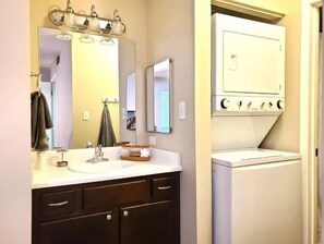 Une salle de bain avec un lavabo blanc, des meubles sombres, un miroir et des toilettes blanches.