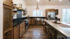 A modern kitchen with wooden cabinets, a stainless steel refrigerator, and a large island. - Honeysuckle Bridge- Hot Tub, Firepit, Private Hiking, Sandstone Arch (Campton)