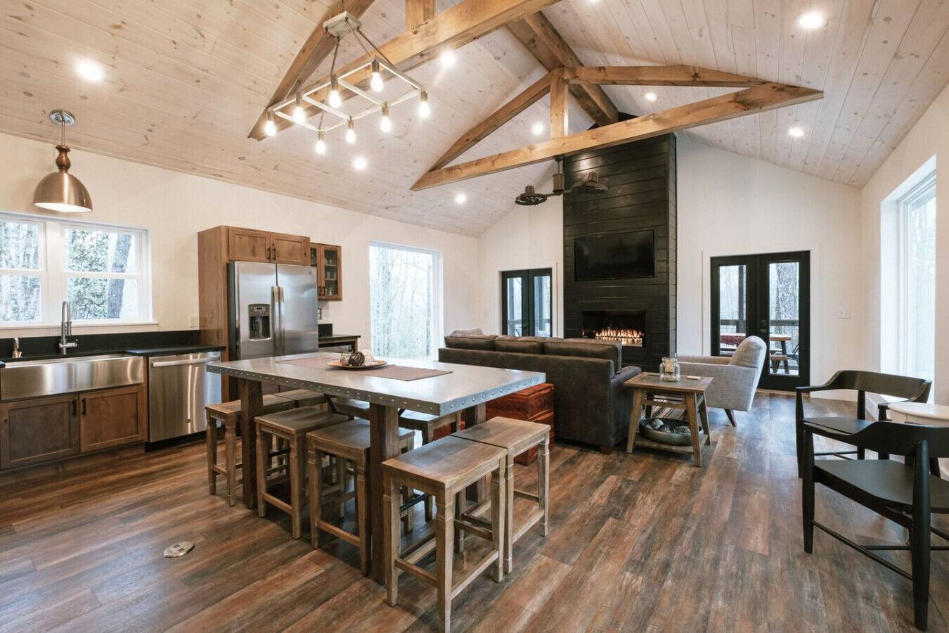 A spacious kitchen with a central island, wooden beams, and a large fireplace.