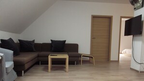 A modern living room with a brown sectional sofa, a small wooden coffee table, and a TV mounted on the wall. - MyHome10, Wiesbaden - Mainz (Wiesbaden)