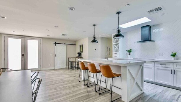 A modern kitchen with a central island, bar stools, pendant lighting, and a large window. - Luxurious Old Town Remodel Home W/ Heated Pool (Scottsdale)
