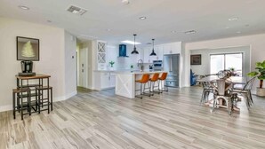 A spacious kitchen with a central island, modern pendant lighting, and a dining area with a round table and chairs. - Luxurious Old Town Remodel Home W/ Heated Pool (Scottsdale)