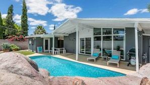 Ein modernes Haus mit Swimmingpool, Außenbereich mit Sitzgelegenheiten und einer überdachten Terrasse.
