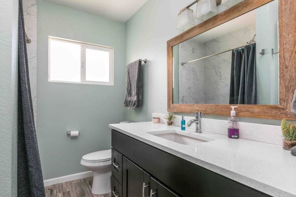 A bathroom with a white sink, a mirror, and a toilet.