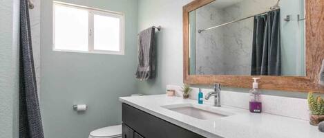 A bathroom with a white sink, a mirror, and a toilet.