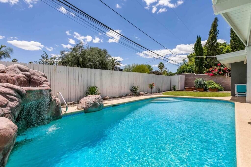 Un jardín trasero con piscina, valla de madera y jardinería.