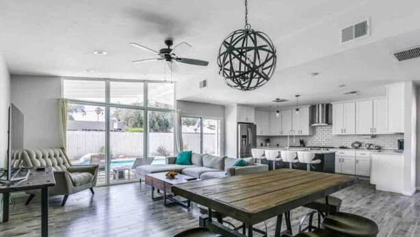 Eine moderne Küche mit weißen Schränken, einem Holztisch und einem Deckenventilator.