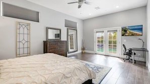 A bedroom with a bed, a desk, a chair, a ceiling fan, and a sliding glass door leading to a balcony. - New Remodel In Old Town W/ Heated Pool (Scottsdale)