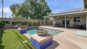 A backyard with a swimming pool, a covered patio, and a brick wall. - New Remodel In Old Town W/ Heated Pool (Scottsdale)