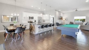 A spacious living area with a pool table, a dining table with chairs, a kitchen with white cabinets, and a bar area. - New Remodel In Old Town W/ Heated Pool (Scottsdale)