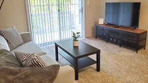Sala de estar com sofá, mesa de centro e televisão.