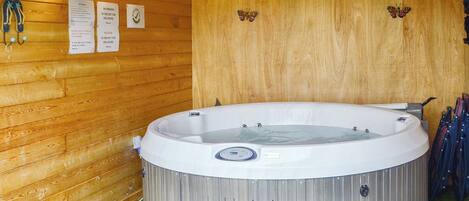 Un bain à remous dans une pièce en bois, avec un mur en bois, un panneau indiquant qu'il est interdit de fumer et une décoration en forme de papillon.