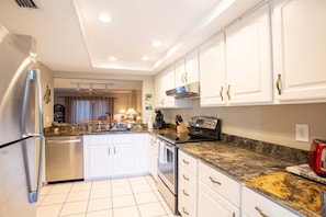 A modern kitchen with white cabinets, stainless steel appliances, and granite countertops.