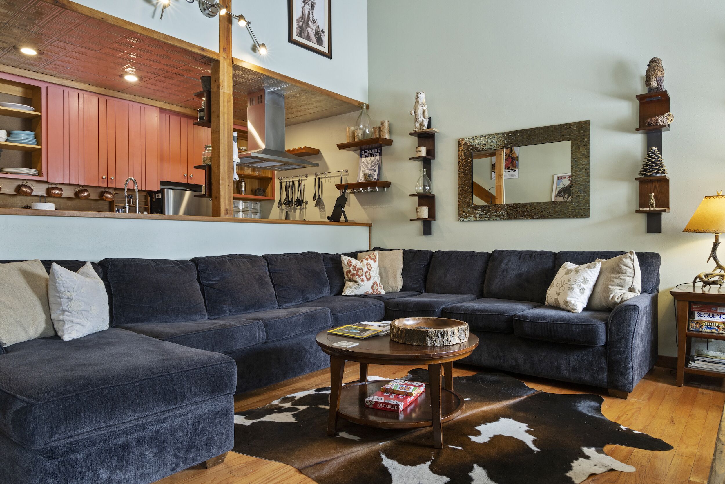 A living room with a dark blue sectional sofa, a round coffee table, and a cowhide rug.