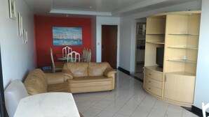 Un salon avec un canapé beige, une table basse blanche et un meuble en bois doté d’étagères.