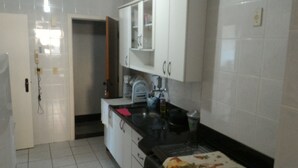 Une cuisine avec des meubles blancs, un plan de travail noir et un pare-feu en carrelage.