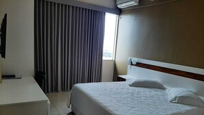 Une chambre d’hôtel avec un lit, un bureau, une chaise et une fenêtre avec des rideaux.
