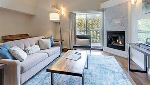 Un salon comprenant un canapé, une table basse, une cheminée et de grandes fenêtres.
