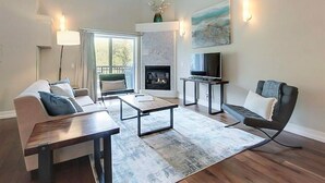 Un salon spacieux avec une cheminée, un ensemble de canapés, une table basse et un téléviseur.