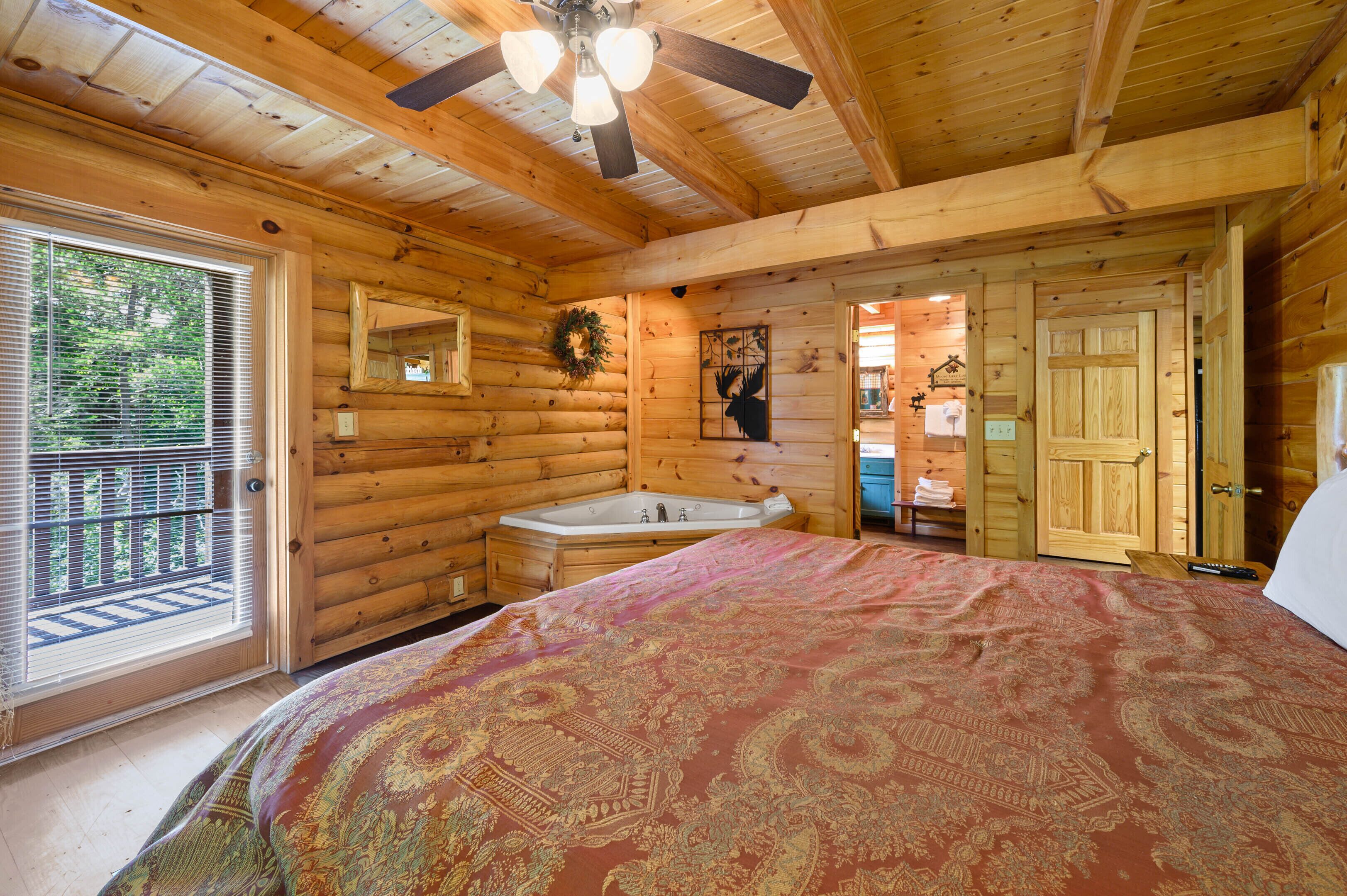 Ein Schlafzimmer in einer Blockhütte mit einem großen Bett, einer Badewanne und einem Deckenventilator.