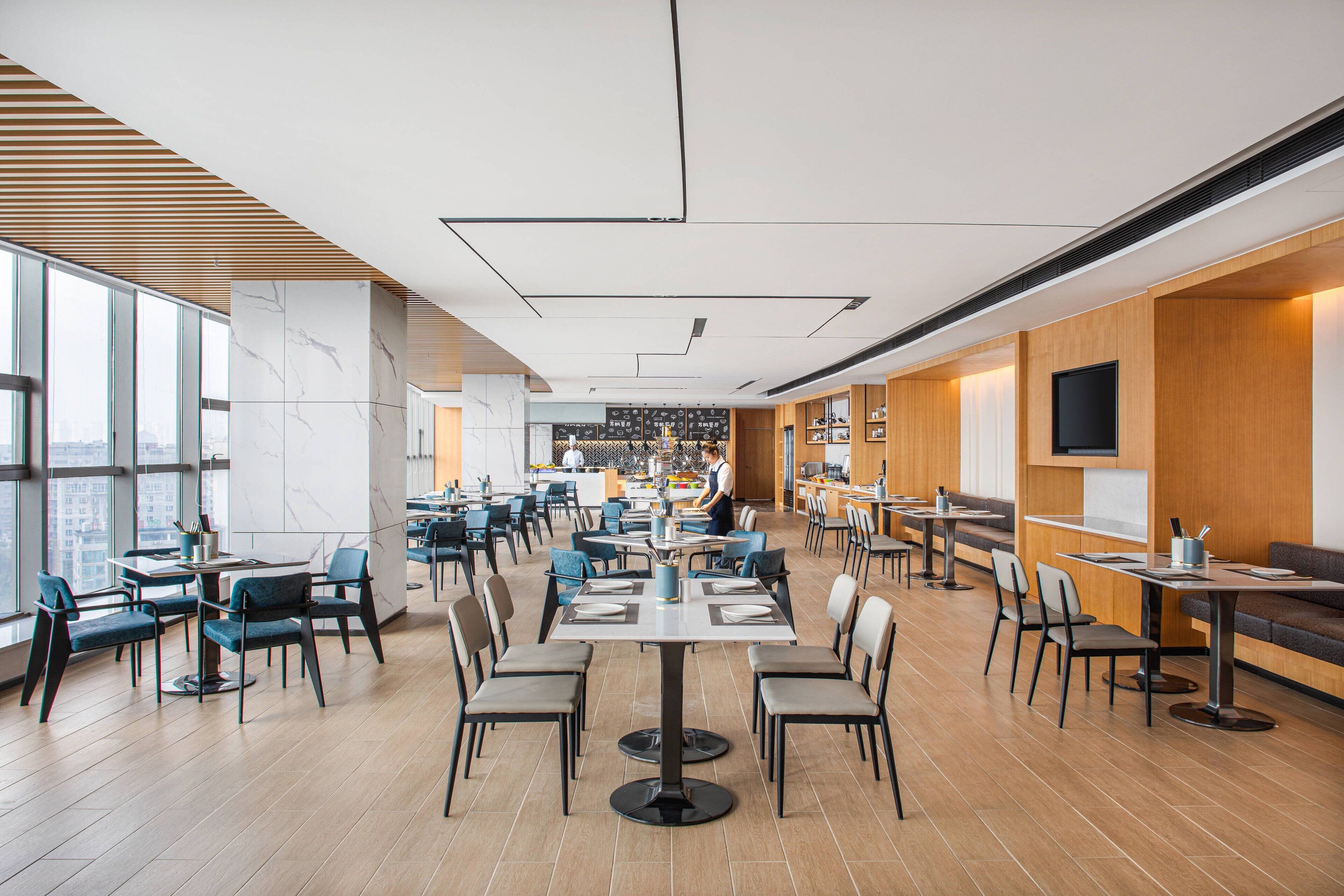 A spacious restaurant with high ceilings, large windows, and a variety of seating arrangements including tables and booths.