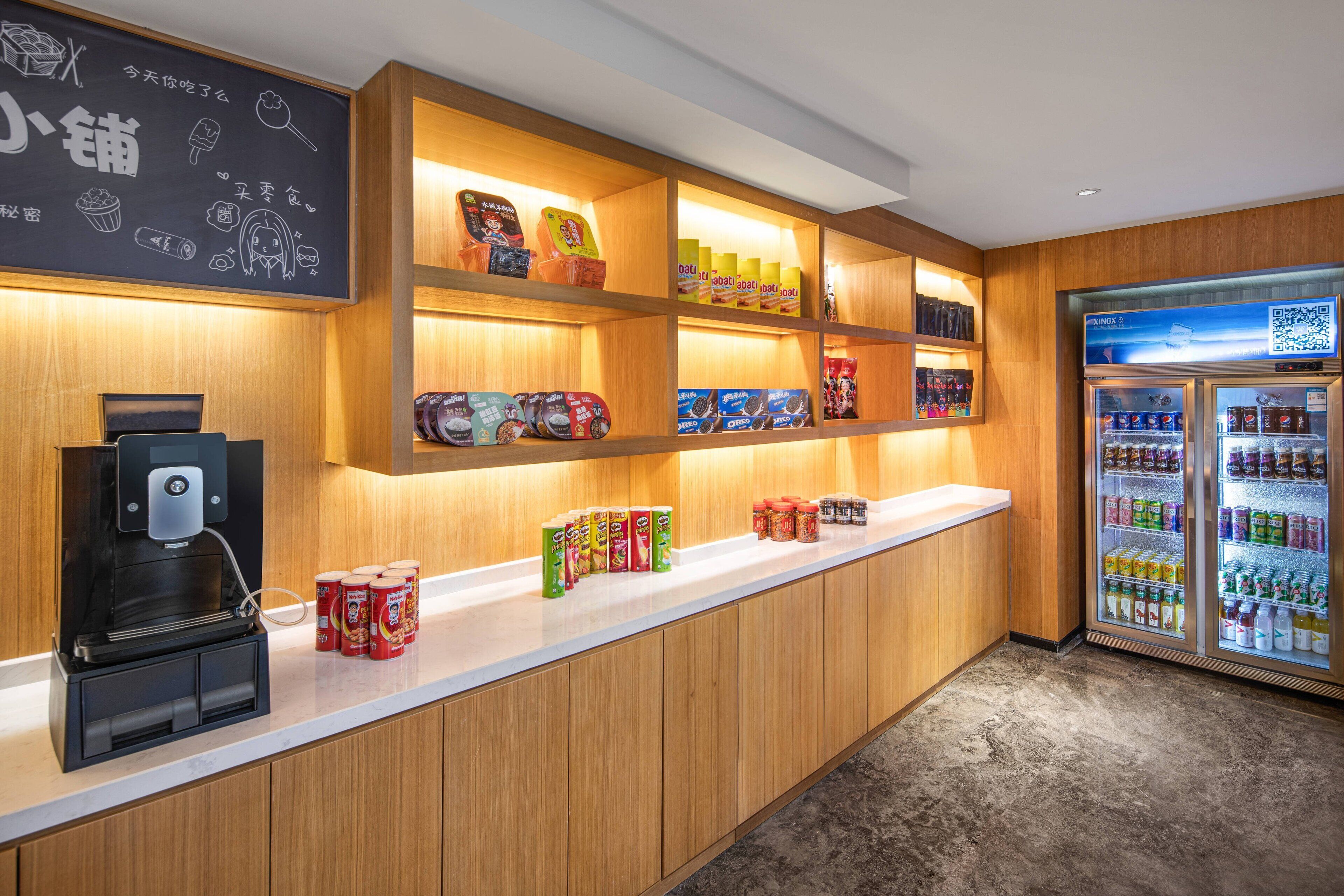 A counter with a coffee machine, shelves with snacks, and a refrigerated display.