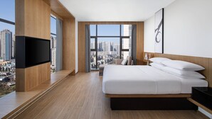 Una habitación de hotel moderna con una cama grande, un televisor de pantalla plana y vistas a la ciudad.