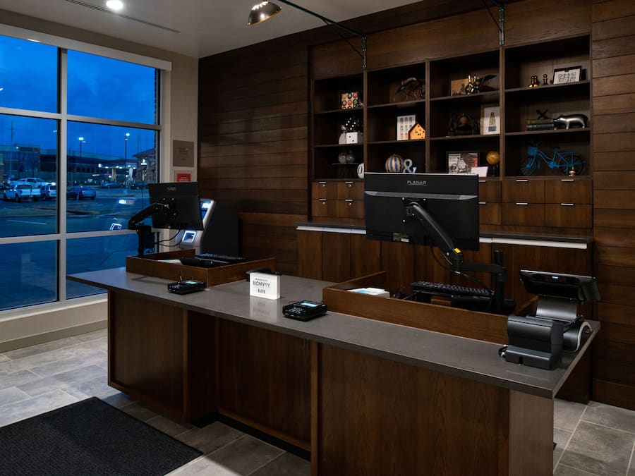 A hotel reception desk with a computer, a cash register, and a sign that reads "Bonvoy Elite."