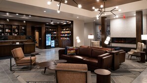 A modern lobby with a seating area, a bar, and a fireplace.